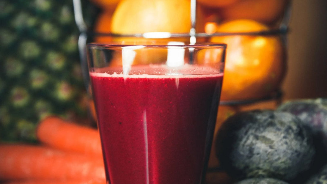 berry smoothie in a glass with various fruits in the background