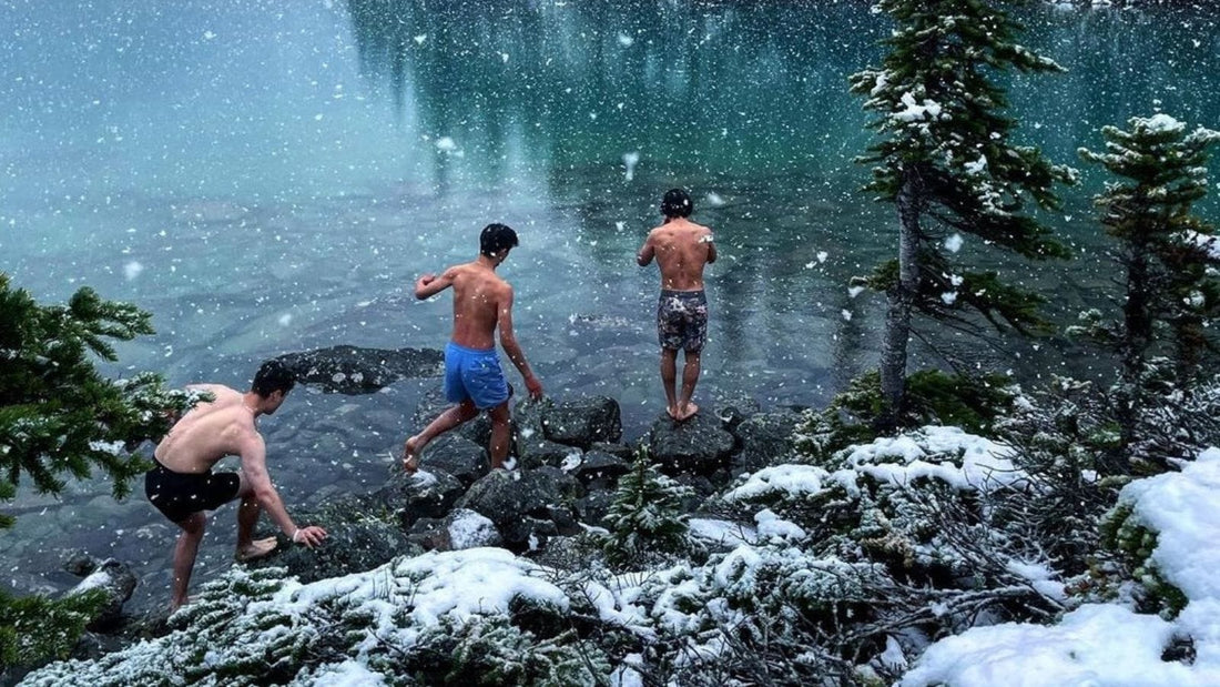 three people walking into a cold lake while snowing